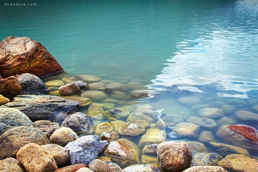 Closeup of rocks in water at lake Louise, Alberta by Sandralise