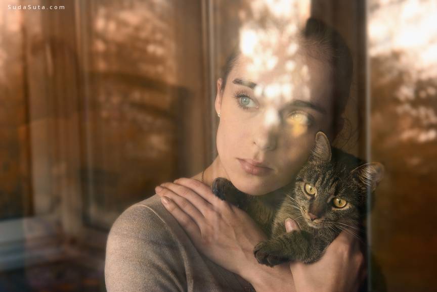 attractive girl holding a cat and sits by the window