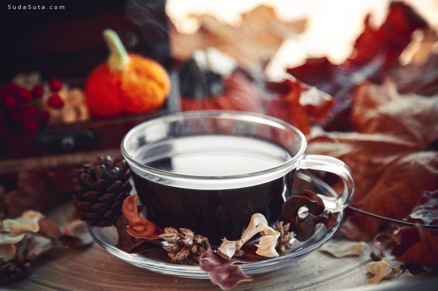 A cup of dark drink with the autumn background